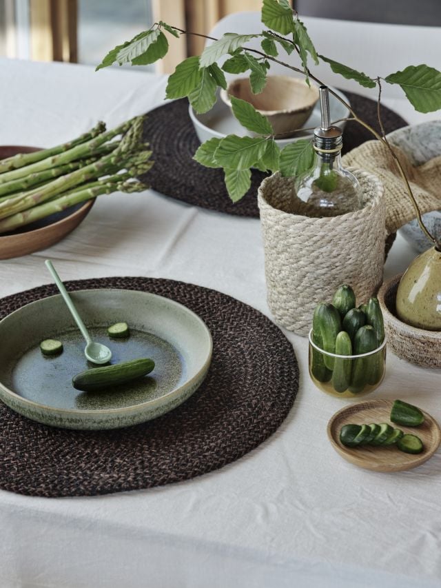 Dukningsinspiration runda bordstabletter i brunsvart gröna accentfärger och bordskorg i flätad jute